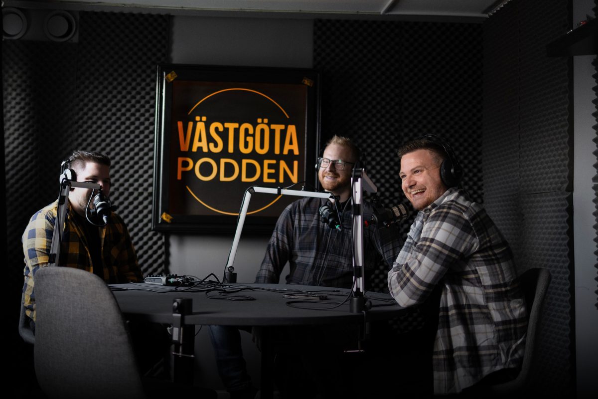 Tre personer sitter i en poddstudio med mikrofoner och spelar in Västgötapodden.